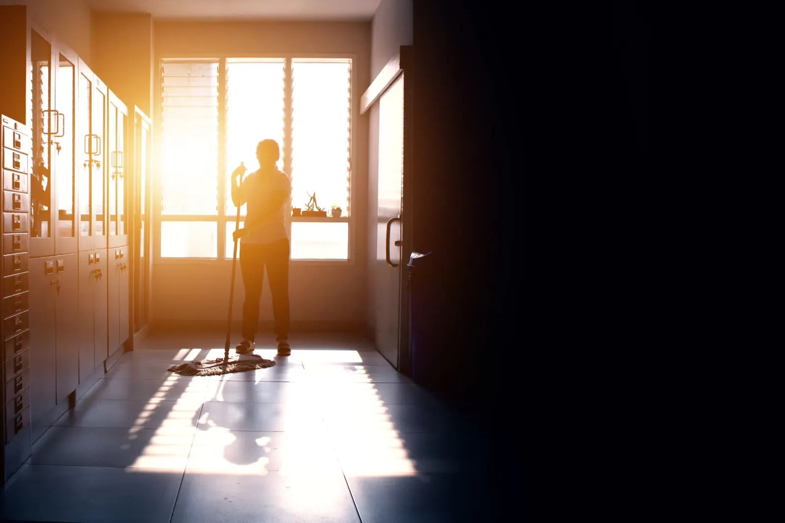 Janitorial attendant mopping a corridor at the end of the day